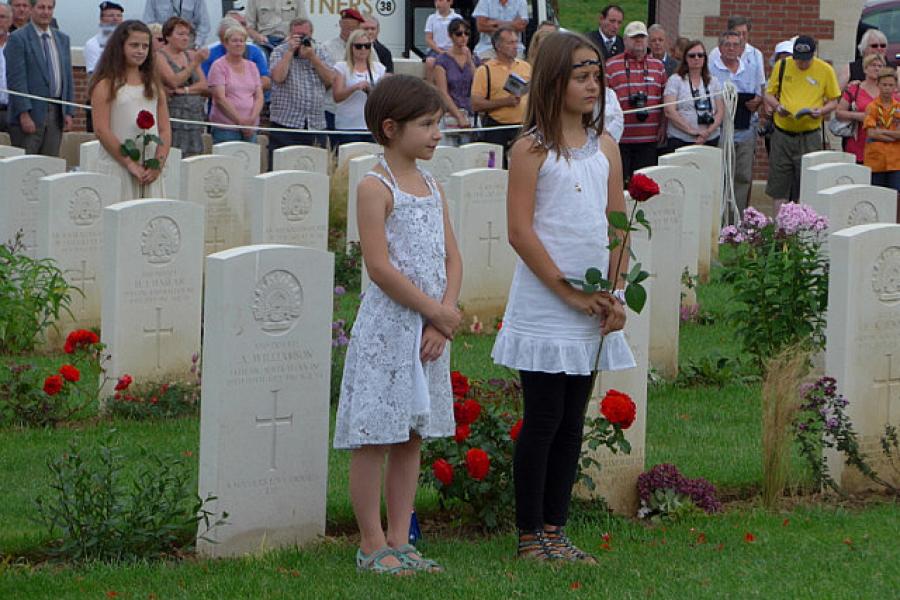 Two Fromelles children carry a red rose