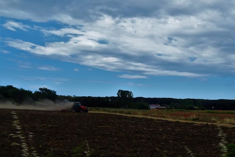 a blue sky circle above a tractor ploughing 