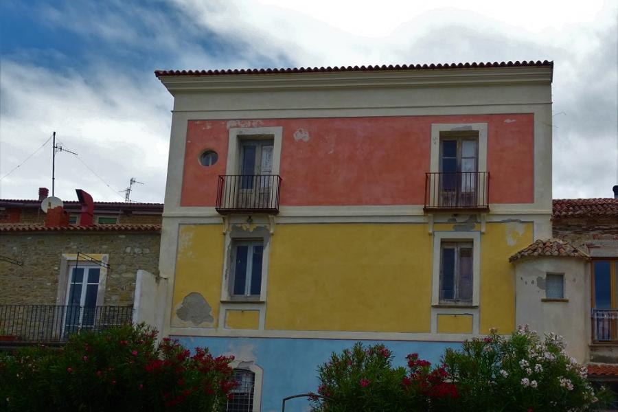 yellow ochre and terracotta red building with blue sky circle above