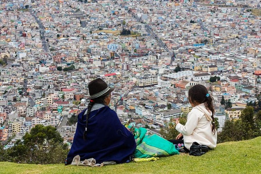 Two girls high on a hillside overlooking dense Quito, Ecuador