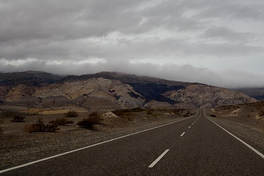 Ruta 40, Argentina - Paved road leading to low mountains in the distance on an overcast day.