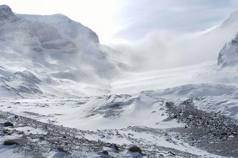 Icefields Parkway - Columbia Icefield in winter with snow blowing at higher altitude.