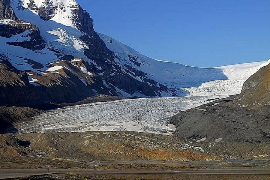 Icefields Parkway - Glacier in the summer. Exposed gravel areas with the highway in miniature in the foreground.