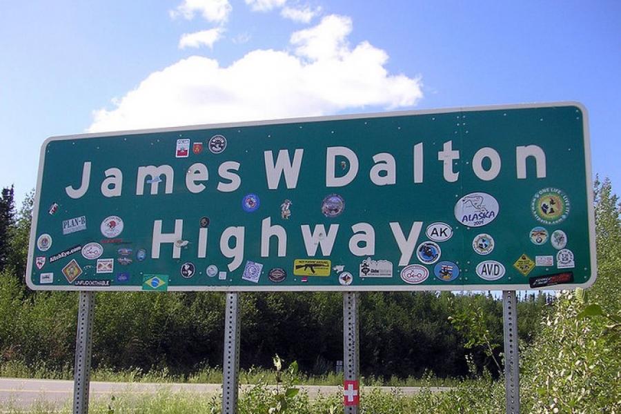 Dalton Highway - Transportation road sign that indicates "James W. Dalton Highway". Sign is greated dotted with travel and logo stickers all over it. Sign is still legible, though.